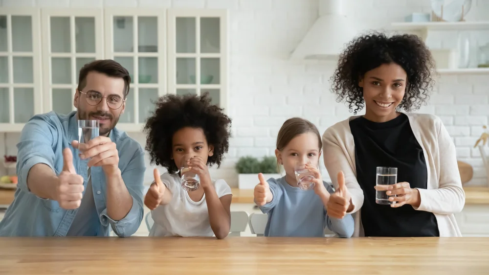 Familie mit Wassergläsern am Küchentisch